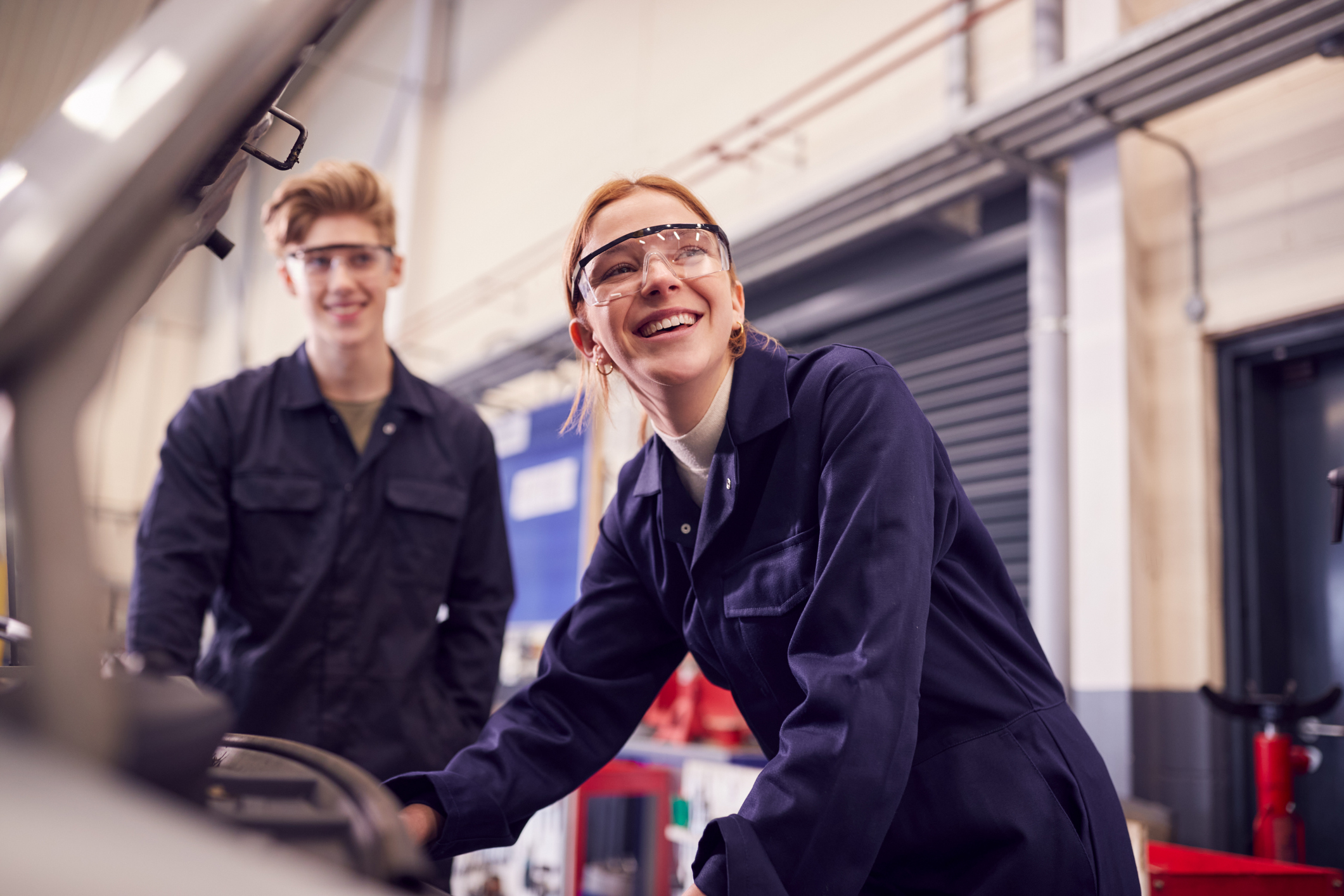 Two young adult mechanics standing in a workshop