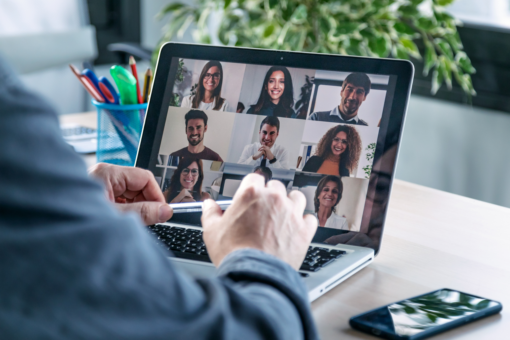 Man sitting in front of an Ipad taking a video call with a group of people.